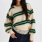 Person wearing a cream and green striped sweater with lace detail on a white background